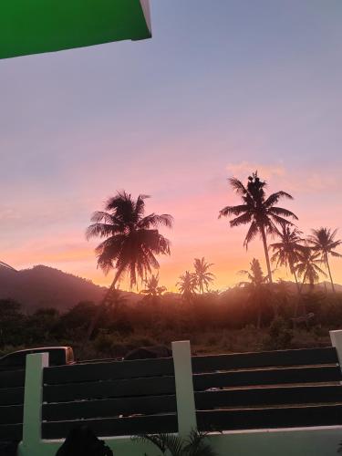 a bench with palm trees in front of a sunset at PRIVATE VILLA FRONT BEACH Infinity Pool in San Vicente