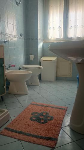 a bathroom with two toilets and a sink and a rug at La Maison in Teulada