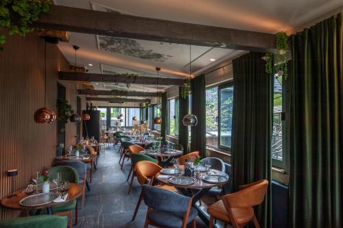 a dining room with tables and chairs and windows at Ethno Houses Plitvice Lakes Hotel in Plitvica selo
