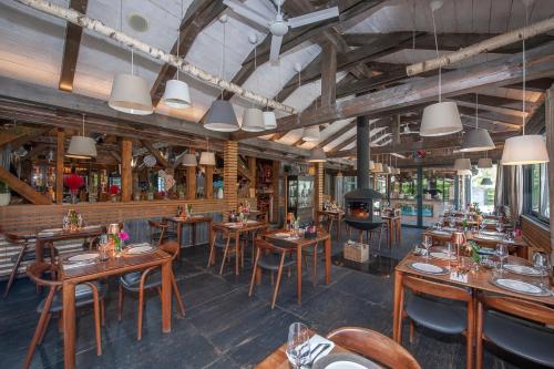 a restaurant with wooden tables and chairs and a fireplace at Ethno Houses Plitvice Lakes Hotel in Plitvica selo