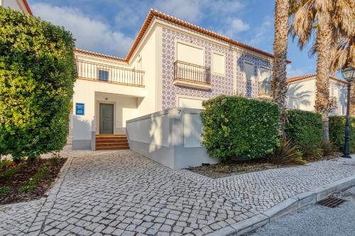 an exterior view of a house with a palm tree at Praia D'el Rey - A4 in Óbidos