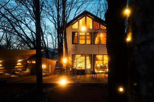 a house lit up at night with lights at 8Lantern サウナ付き民泊で日本10位 最大10名 大きな窓とウッドデッキの一体感 2025年完成 BBQ 貸し切り宿 in Yamanakako