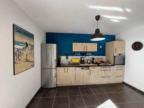 une cuisine avec des armoires en bois et un réfrigérateur dans l'établissement Bord de plage, à Bretignolles-sur-Mer