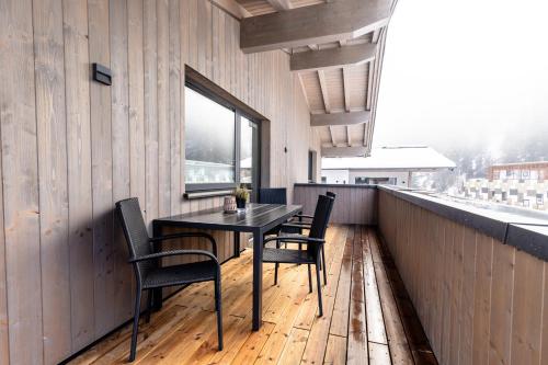 a table and chairs on a balcony with a window at Appartement Hoamatgfüh in Saalbach-Hinterglemm