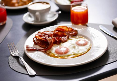 a plate of food with bacon and eggs on a table at Hotel Molino Rosso in Imola