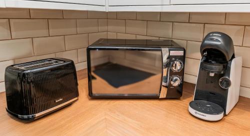 a microwave next to a toaster and a blender at Newly Furnished Cosy 3 bed 20mins from City Center in Manchester