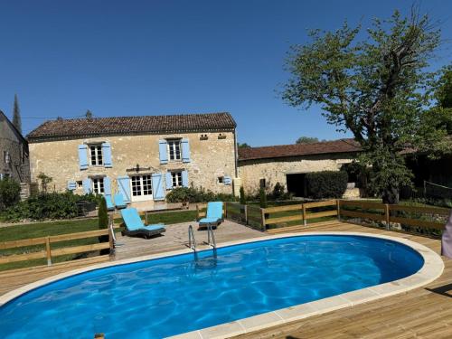 une piscine avec deux chaises et une maison dans l'établissement Domaine Le Nourrissat, à Savignac-de-Duras