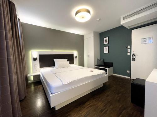 a bedroom with a white bed and a green wall at zeitwohnhaus SUITE-HOTEL & SERVICED APARTMENTS in Erlangen