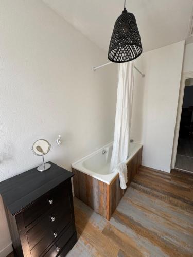 a bathroom with a bath tub and a table and a lamp at Cottage-Saint Laurent sur Sèvre in Saint-Laurent-sur-Sèvre
