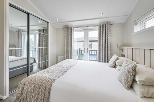 a white bedroom with a large bed and a balcony at Host & Stay - Roseberry View Lodge Retreat in Great Ayton