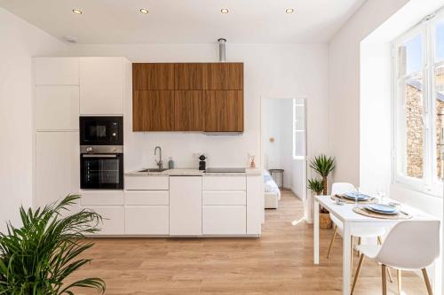 une cuisine avec des armoires blanches et une table blanche dans l'établissement Appartement neuf 2 pièces Port, à Nice