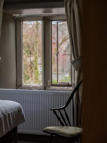 a bedroom with a bed and a chair and a window at The Buck Inn, Malham in Malham