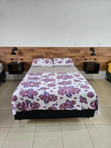 a bedroom with a bed with a floral bedspread at Casa no centro de Navegantes in Navegantes