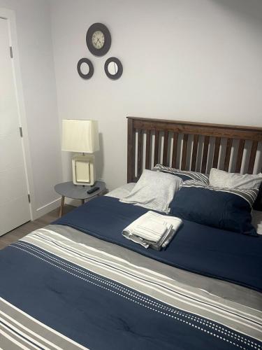 a bed with a blue blanket and a clock on the wall at Peaceful Haven in Saskatoon