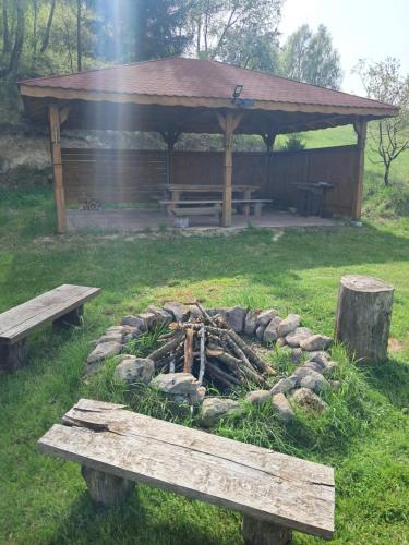 a fire pit in a field with two benches at Gucio in Zwierzyniec