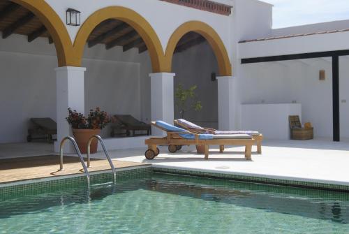 ein Pool mit einer Bank neben einem Haus in der Unterkunft Cortijo de Vega Grande in Llerena