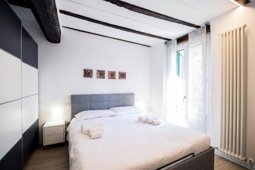 a white bedroom with a large bed with two pillows at Tesoro Dé Galluzzi in Bologna