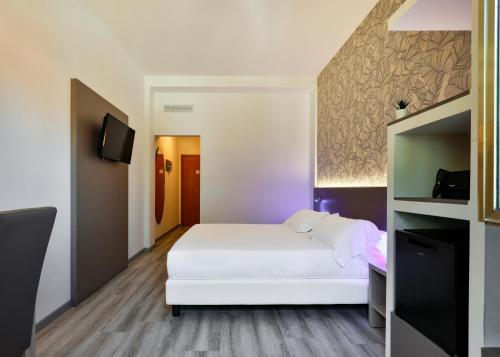 a bedroom with a white bed and a tv at Hotel Molino Rosso in Imola