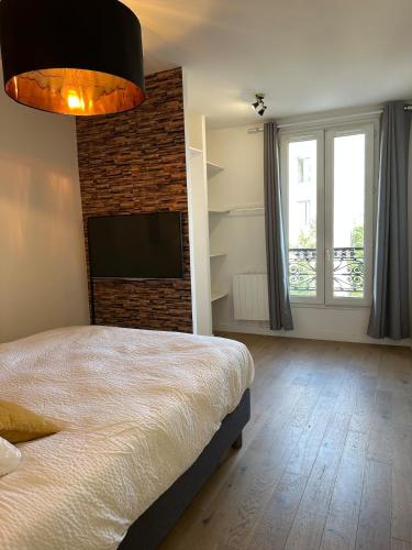 une chambre avec un lit et une télévision à écran plat dans l'établissement Charmant 2P lumineux aux portes de Paris, à Ivry-sur-Seine