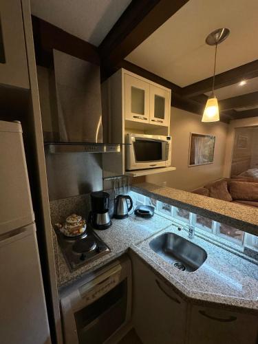 a small kitchen with a sink and a microwave at Flat Luxo 3010 com banheira Mountain Village Laje de Pedra Canela in Canela