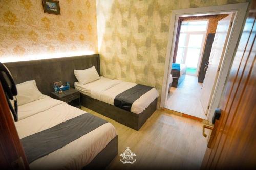 a hotel room with two beds and a sliding glass door at Vote Hotel 2 in Erbil