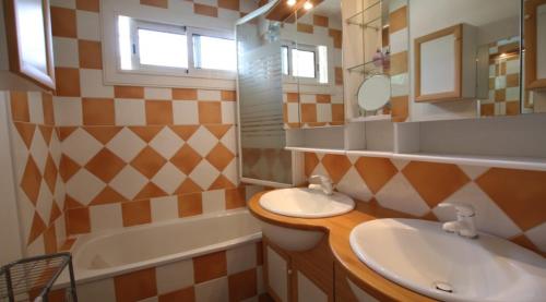 une salle de bain avec deux lavabos, une baignoire et un miroir dans l'établissement PROVENCE VAUCLUSE VELLERON Superbe maison avec piscine tout confort, à Velleron