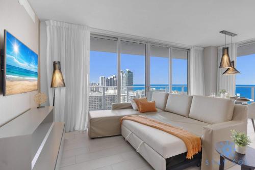 Una sala de estar con un sofá y grandes ventanales. en High-Floor with Stunning Views-Luxury Condo - Pools, en Hollywood