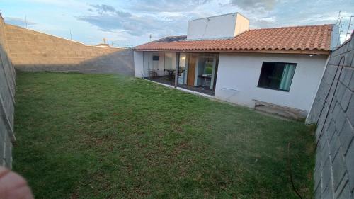 a backyard of a white house with a yard at Edicula paixão in Muzambinho