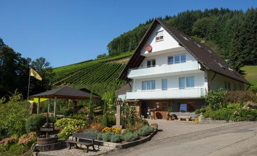 a large white building with a bunch of plants in front at Ferienwohnung Baßler in Kappelrodeck