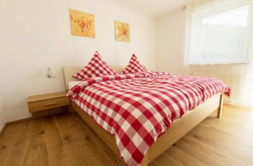 a bed with a red and white checkered blanket at Ferienwohnung Baßler in Kappelrodeck