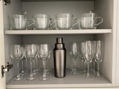 a row of wine glasses and a bottle on a shelf at Walcot Yard with parking, Bath Keys in Bath