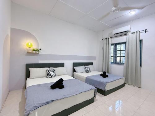 Dos camas en una habitación con dos gatos negros sentados en ellas. en Outdoor BBQ Air Putih 4R3B Homestay, en Kuantan