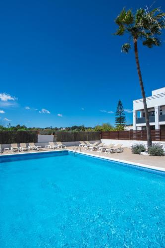 a large swimming pool with chairs and a palm tree at Pierre & Vacances Ros Ibiza in Santa Eularia des Riu