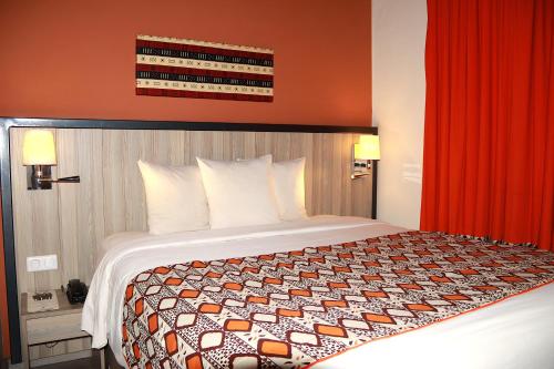 a large bed in a hotel room with red curtains at ONOMO Hotel Bamako in Bamako