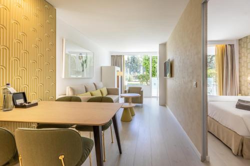 a hotel room with a bed and a table and chairs at Hotel Illa d'Or & Club Apts 4* Sup in Port de Pollensa