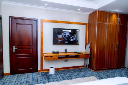 a bedroom with a desk and a tv on the wall at Kigali Paramount Hotel in Kigali