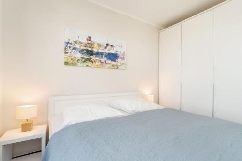 une chambre blanche avec un lit et un tableau au mur dans l'établissement Strandresidenz Vogelflug Penthouse 14, à Fehmarnsund