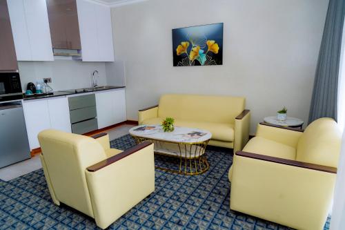 a living room with yellow chairs and a table at Kigali Paramount Hotel in Kigali