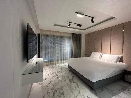 a bedroom with a large white bed and a tv at Crowne Apartments in Mamaia