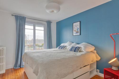 - une chambre avec des murs bleus et un lit avec des oreillers dans l'établissement L'Escale Maison Bleue proche chantiers atlantique, à Saint-Nazaire