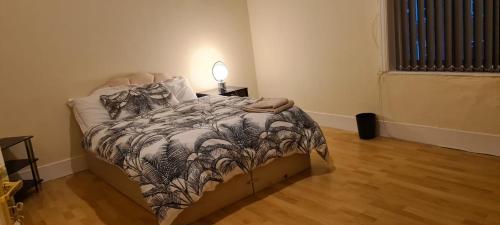 a bedroom with a bed with a comforter and a lamp at Cosy 3 bedroom house in Leigh