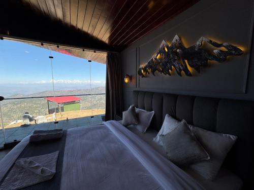 a bedroom with a large bed with a large window at Harmony Heights in Mukteswar