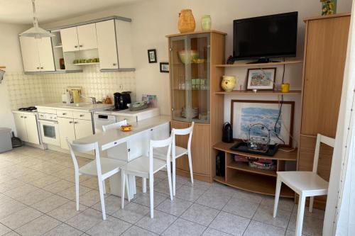 Il comprend une cuisine avec une table et des chaises ainsi qu'une télévision. dans l'établissement Maison 3 chambres à louer pour les vacances Grau du Roi, au Grau-du-Roi