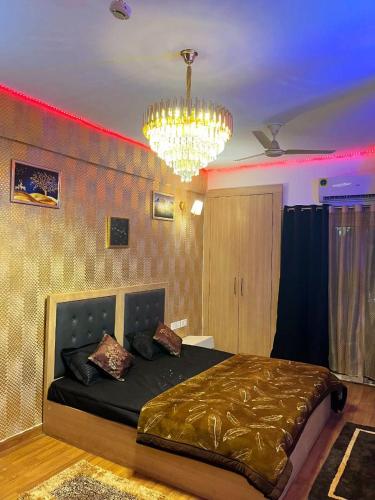 诺伊达Palm Breeze Luxury Studio Apartment的一间卧室配有一张带吊灯的大床