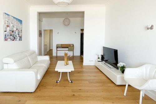 un salon avec un canapé blanc et une télévision dans l'établissement Seafront Apartment for 6 Promenade des Anglais, à Nice