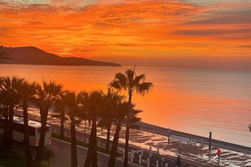 - un coucher de soleil sur une plage avec des palmiers et l'océan dans l'établissement Seafront Apartment for 6 Promenade des Anglais, à Nice