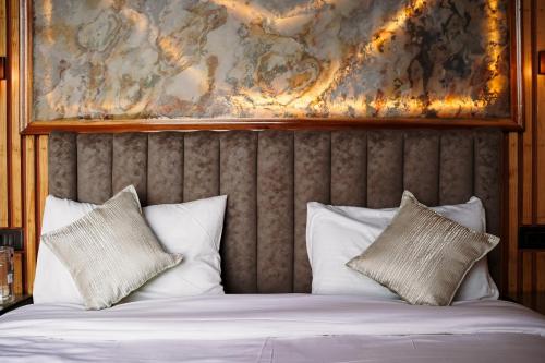 a bed with white pillows and a painting on the wall at Harmony Heights in Mukteswar