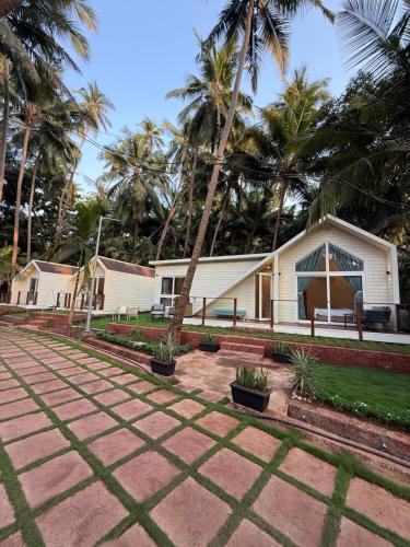 a house with palm trees in front of it at Sea Breeze, Guhagar in Guhagar