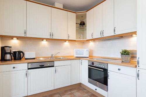 a white kitchen with white cabinets and a sink at Hafen 13 Hafenblick 1 in Laboe