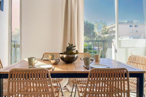 une table de salle à manger avec des chaises et une grande fenêtre dans l'établissement Magnifique Appartement - M3, à Saint-Tropez